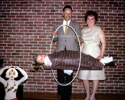Floating girl through a hoop, brick wall, man woman, magician, magic, 1960s