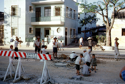 Children playing in the middle of road construction, houses, homes, Macau China, September 1962