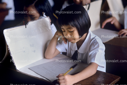 Girl writing and reading in classroom