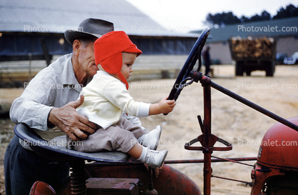 Grandpa teaches grandson to drive tractor, January 1960, 1960s