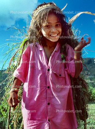 Girl carrying vegetation, smiles, deforestation, desertification