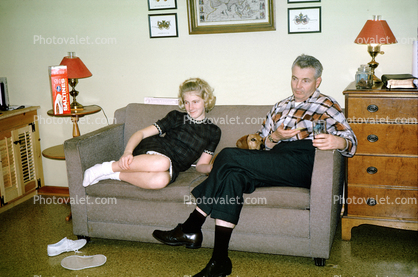 Man, Woman sit on a sofa, couch, lamps, saltine crackers, socks, Dog, 1950s