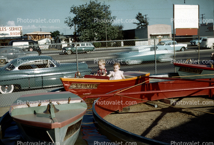 Stevie, girl and boy in a kiddie ride, boats, water, cars, 1950s