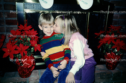 girl kisses boy, brother, siblings, stockings, fireplace, brick, poinsettia