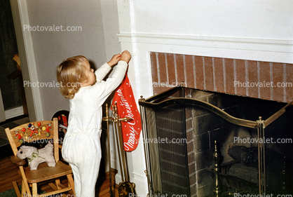 Girl hangs her Christmas Stocking, fireplace, 1950s