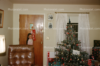 Happy girl with her stocking, door, decorated tree, 1950s