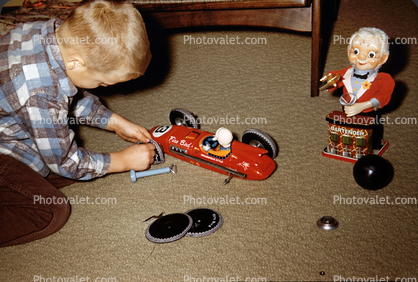 Boy with Fire Bird Toy Race Car fixing tires, 1950s
