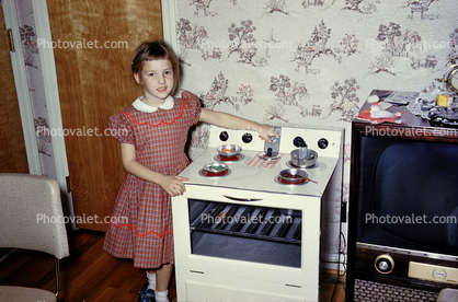 Girl with her toy oven and stove, frying pan, 1960s
