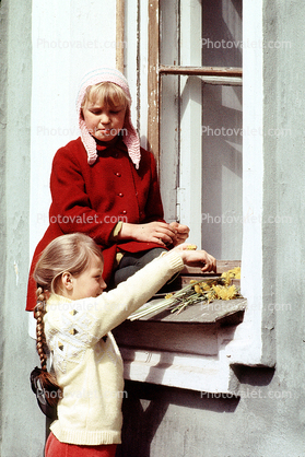 Girls playing with flowers, windowsill, braided hair, cold, coats, hats, sweaters, April 1971, 1970s