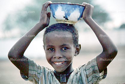 Smiling Boy Carrying a Bowl on his Head, Somalia