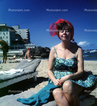 Woman sitting on the beach, flowery dress, sand, 1950s