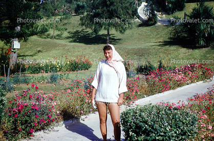 Woman in very short dress, flower garden, path, smile