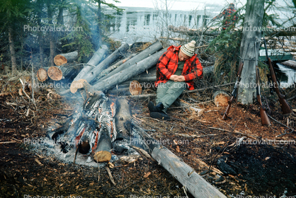 Hunter sleeping by a campfire, logs, guns, rifles, 1950s