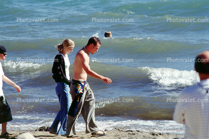 Man and Woman walking in a crowded beach, seashore, waves