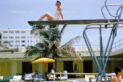 Sitting high on a diving board, sunning, motel, 1950s