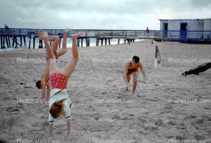 Girl and boys, handstand, beach, 1960s