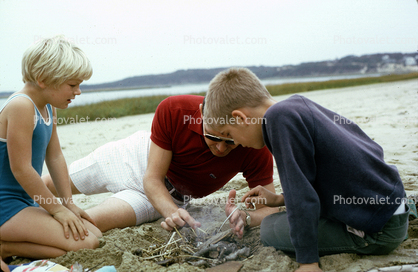 Dad with Daughter and Son, beach, sand, starting a fire, 1960s