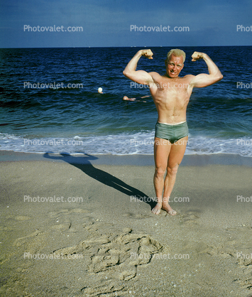 Muscle Beach, Man flexing muscles, water, sand, suntan, 1950s