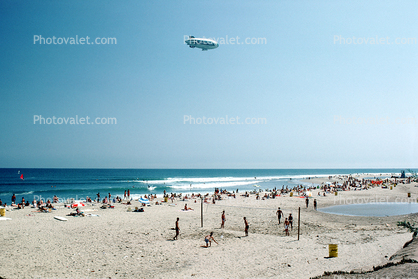 Volleyball, beach, sun worshipers, crowds, people, shoreline, Airship Industries Skyship 500, G-SKSB Blimp, Pacific Ocean