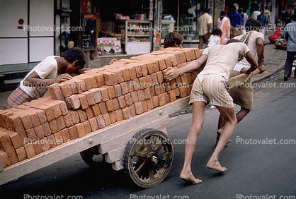 Men pushing and pulling on a cart with bricks, on the Streets of Mumbai