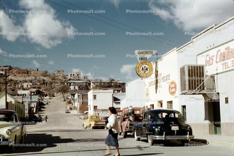 Woman crossing the street, Cars, shops, stores, Homes on a hill, houses, buildings, 1950s