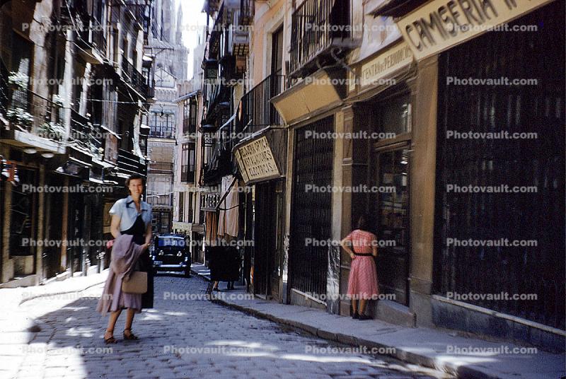 Cobblestone Street, woman, sidewalk, buildings, shops, narrow street, 1940s