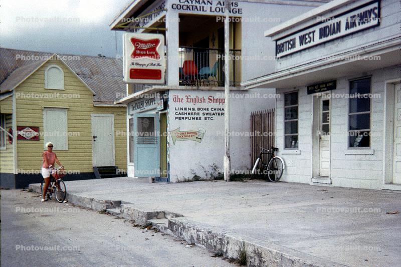 British West Indian Airways, ticket office building, shops, woman on a bike
