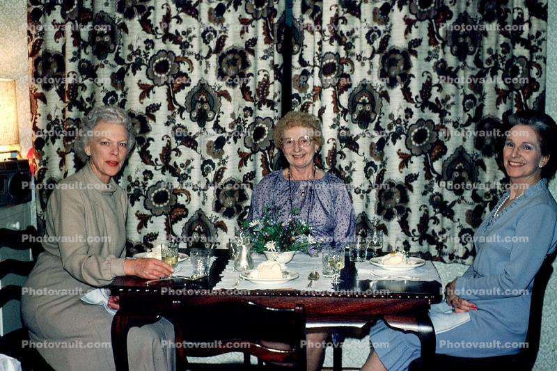 Women eating a dessert, curtains, table setting