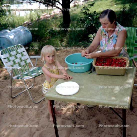 Girl and Grandmother cleaning strawberries, table