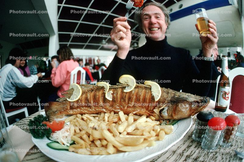 My buddy Don, eating to the bone, beer, fish, fries, plate, salt shaker