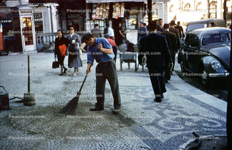 Man sweeping damaged tile, sidewalk, VW-Bug