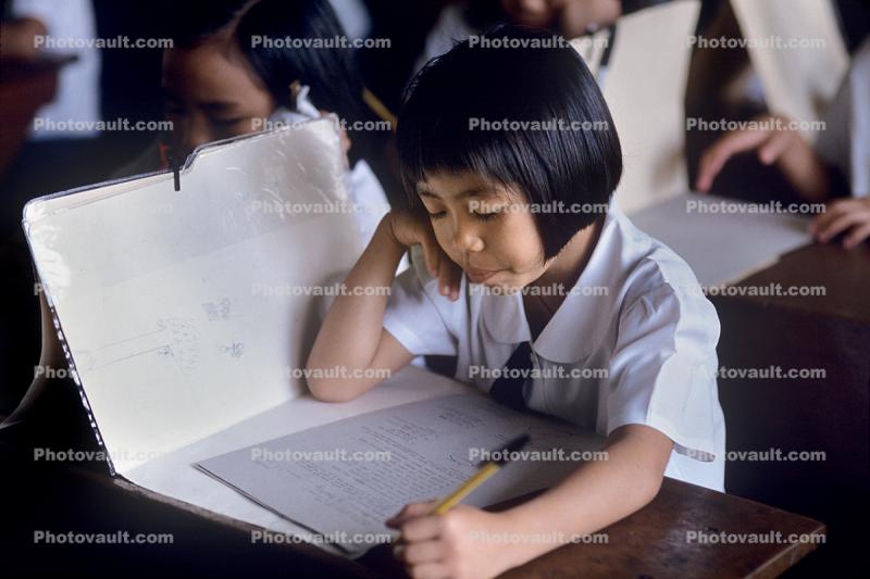 Girl writing and reading in classroom