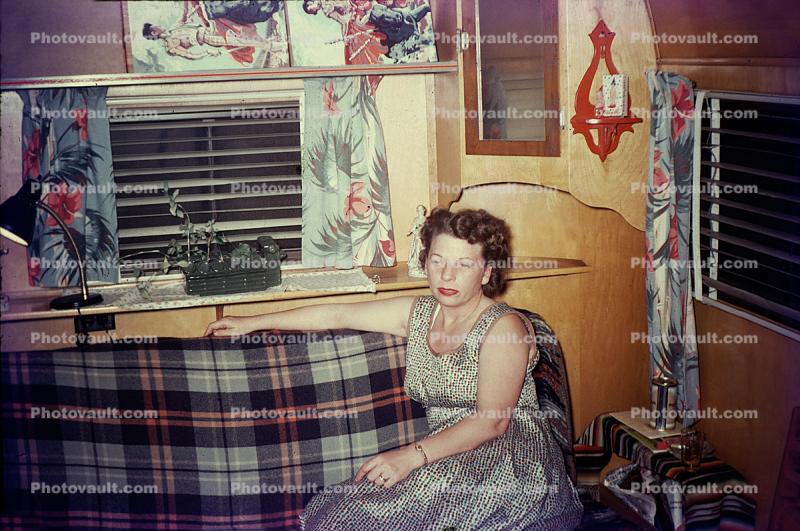 Woman sitting on a Sofa, inside a trailer, windows, 1940s