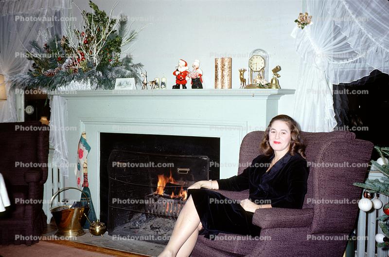 Smiling Lady Sitting, mantle, fireplace, curtains, Christmas decorations, 1950s