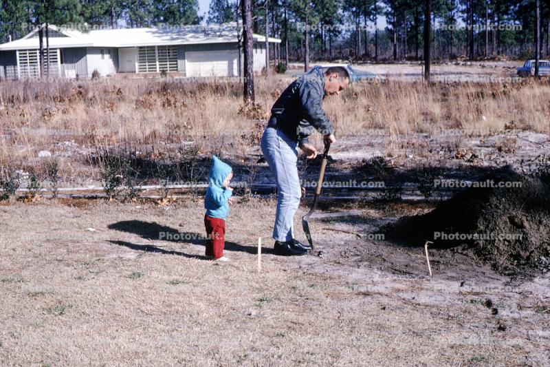 Man working on a cold winter day, shovel, child, 1960s