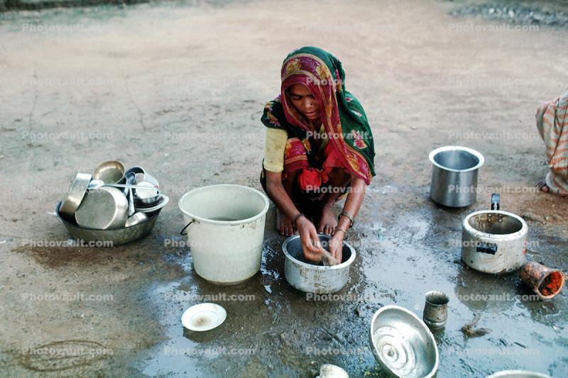 Woman washing dishes, pail, pots, pans