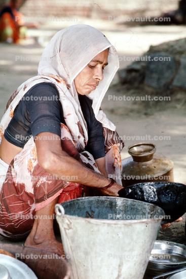 Woman washing dishes, pail, pots, pans