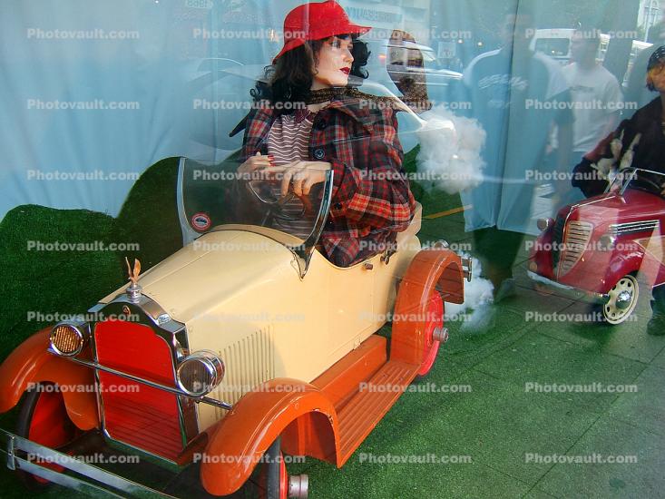 Woman rides a pedal car, jalopy, hat
