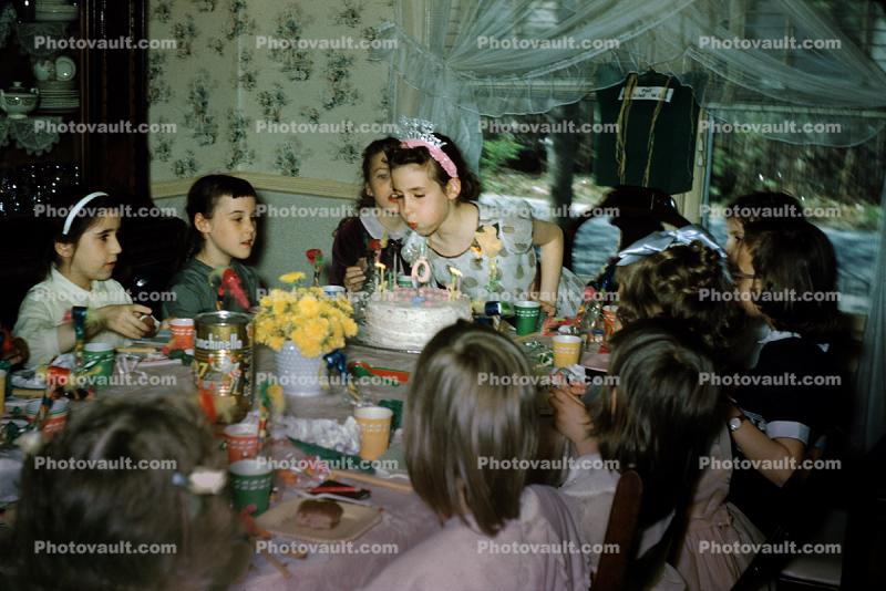 Girl Celebrating being Nine Years Old, blowing out candles, cake, tiara, 1950s