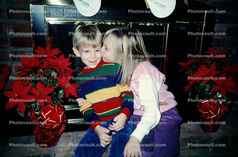 girl kisses boy, brother, siblings, stockings, fireplace, brick, poinsettia