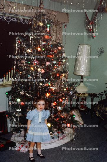 Little Girl stands under a Decorated Christmas Tree