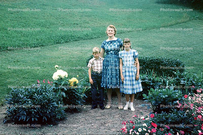 Mother with daughter and son, boy, girl, garden, bench, flowers, 1950s