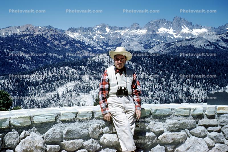 Man sitting on a wall, binoculars, mountains, 1950s