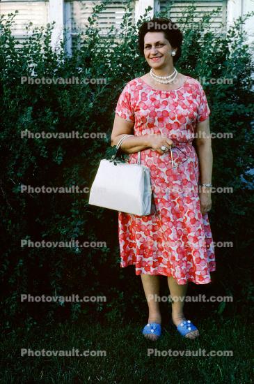 Woman Standing with Purse, dress, smiles. July 1962
