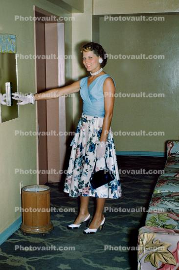 Woman pushing elevator button, purse, dress, 1950s