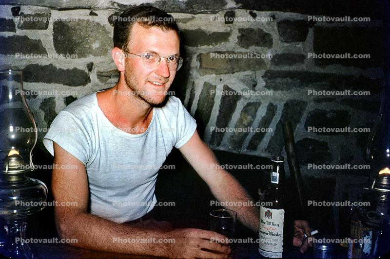 Man drinking hard liquor, T-shirt, fireplace, glasses, 1940s