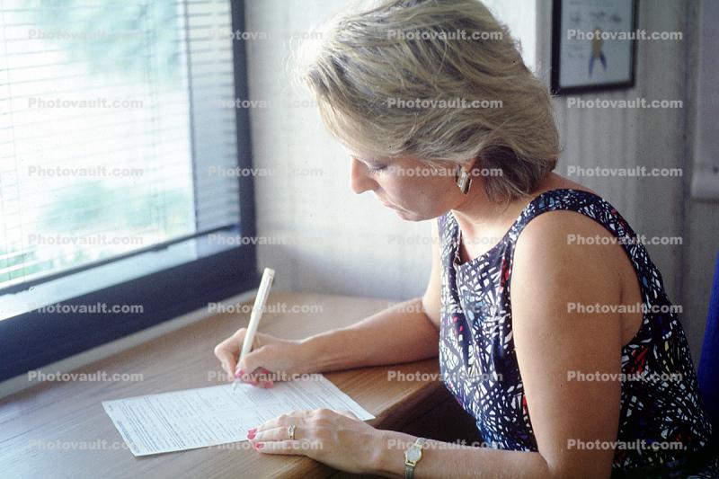 Woman filing out a form, Paper, paperwork, desk, writing, pensive, watch, 1985, 1980s