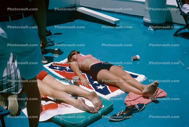 Woman tanning, confederate battle flag towel, bikini, 1965, 1960s