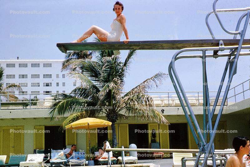 Sitting high on a diving board, sunning, motel, 1950s