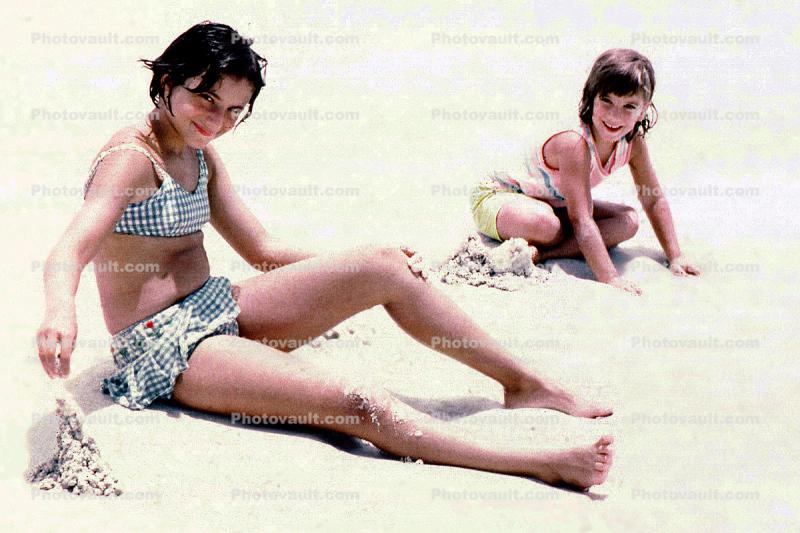Girl sitting on the beach, playing with sand, 1969, 1960s